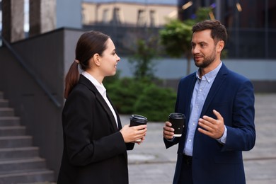 Photo of Coffee to go. Businesspeople with paper cups of drinks near building outdoors