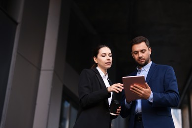 Photo of Coffee to go. Woman with paper cup of drink and her business partner during meeting outdoors, low angle view