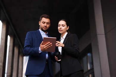 Photo of Coffee to go. Woman with paper cup of drink and her business partner during meeting outdoors, low angle view