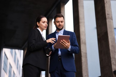 Photo of Coffee to go. Woman with paper cup of drink and her business partner during meeting outdoors, low angle view