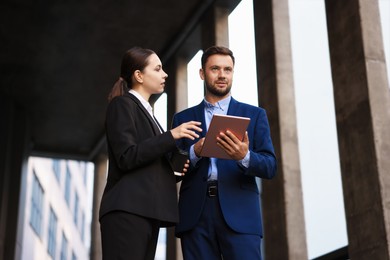 Photo of Coffee to go. Woman with paper cup of drink and her business partner during meeting outdoors, low angle view