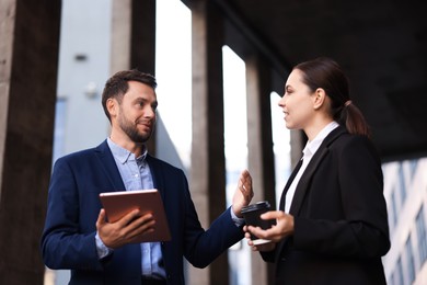 Photo of Coffee to go. Woman with paper cup of drink and her business partner during meeting outdoors, low angle view