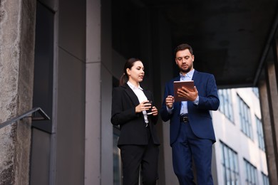 Photo of Coffee to go. Woman with paper cup of drink and her business partner during meeting outdoors, low angle view