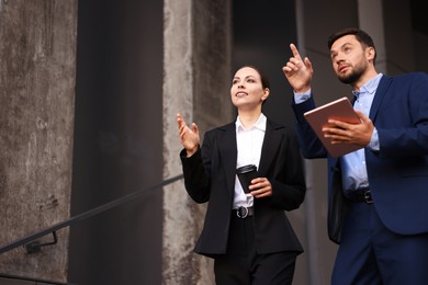 Photo of Coffee to go. Woman with paper cup of drink and her business partner during meeting outdoors, low angle view