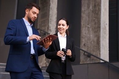 Photo of Coffee to go. Woman with paper cup of drink and her business partner during meeting outdoors, space for text