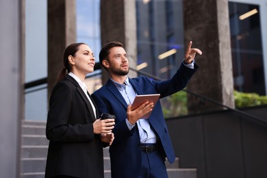 Photo of Coffee to go. Woman with paper cup of drink and her business partner during meeting outdoors