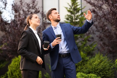 Photo of Coffee to go. Businesspeople with paper cups of drinks outdoors