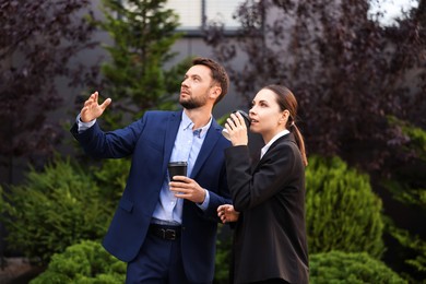 Photo of Coffee to go. Businesspeople with paper cups of drinks outdoors