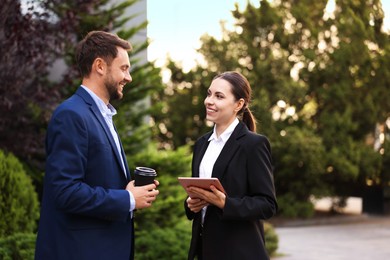Photo of Coffee to go. Man with paper cup of drink and his business partner during meeting outdoors