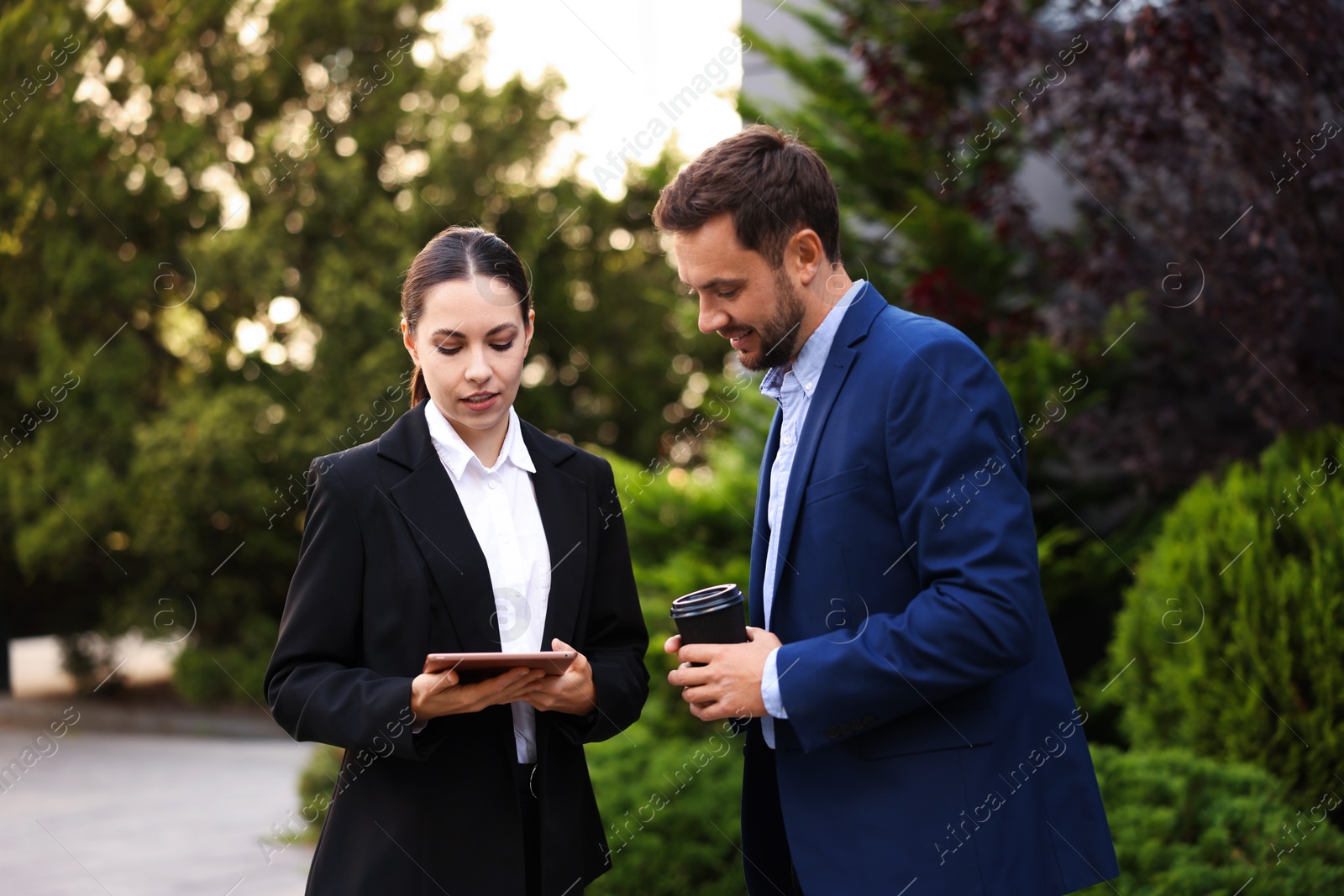 Coffee to go. Man with paper cup of drink and his business partner during meeting outdoors Photo of Coffee to go. Man with paper cup of drink and his business partner during meeting outdoors