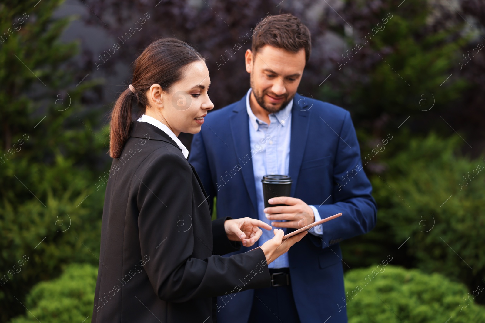 Photo of Coffee to go. Man with paper cup of drink and his business partner during meeting outdoors