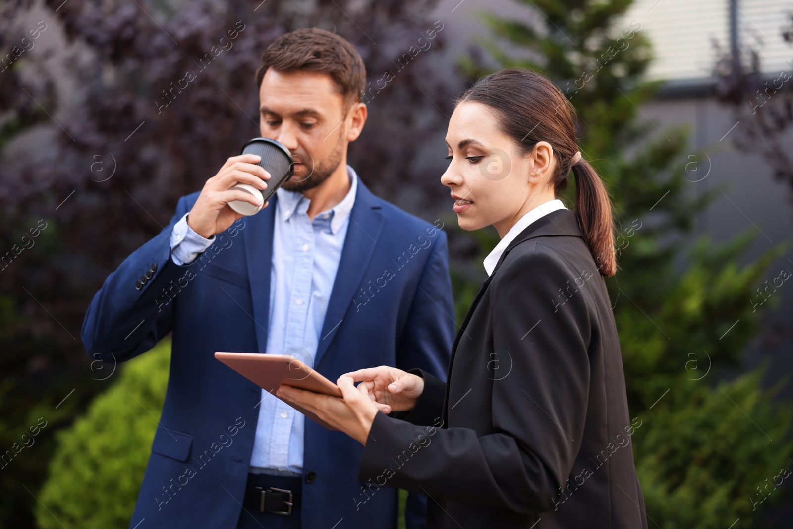 Photo of Coffee to go. Man with paper cup of drink and his business partner during meeting outdoors