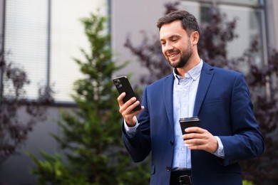 Photo of Coffee to go. Man with paper cup of drink and smartphone outdoors, space for text