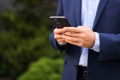 Photo of Businessman using smartphone outdoors, closeup. Space for text