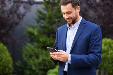 Photo of Businessman using smartphone outdoors, space for text