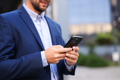 Photo of Businessman using smartphone outdoors, closeup. Space for text