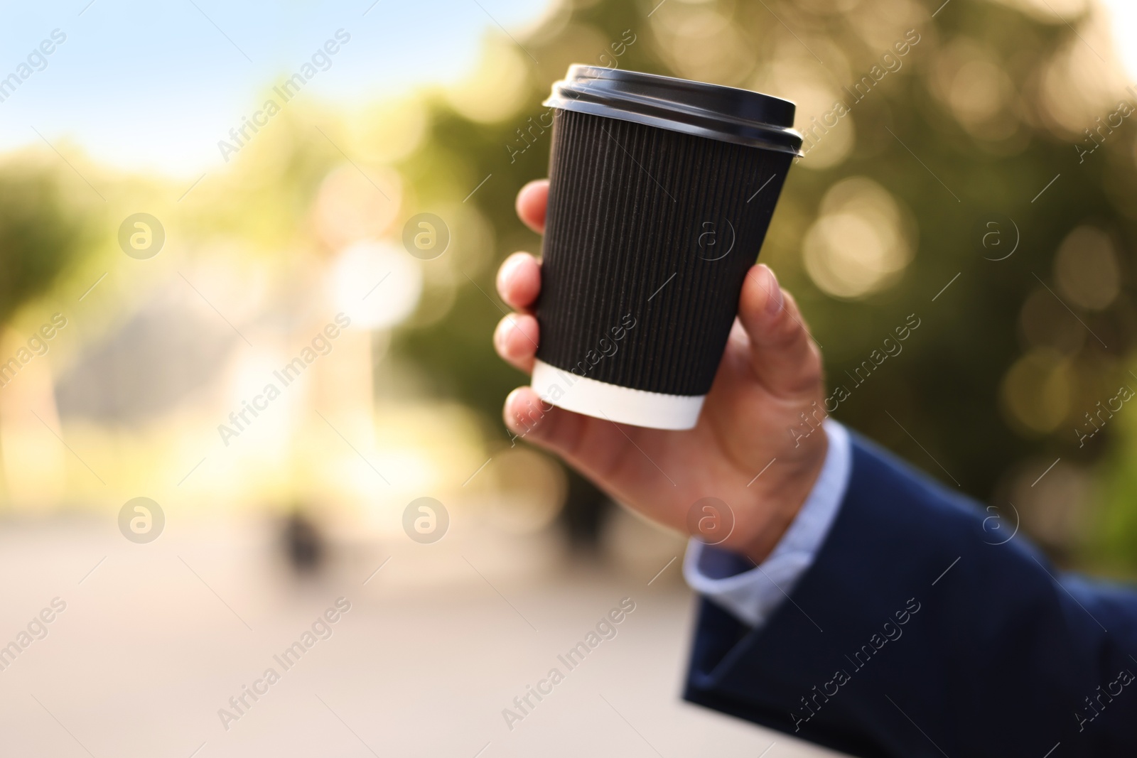 Photo of Coffee to go. Man with paper cup of drink outdoors, closeup. Space for text