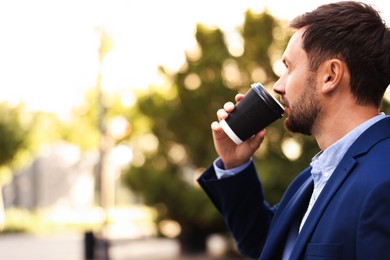 Photo of Coffee to go. Man with paper cup of drink outdoors, space for text