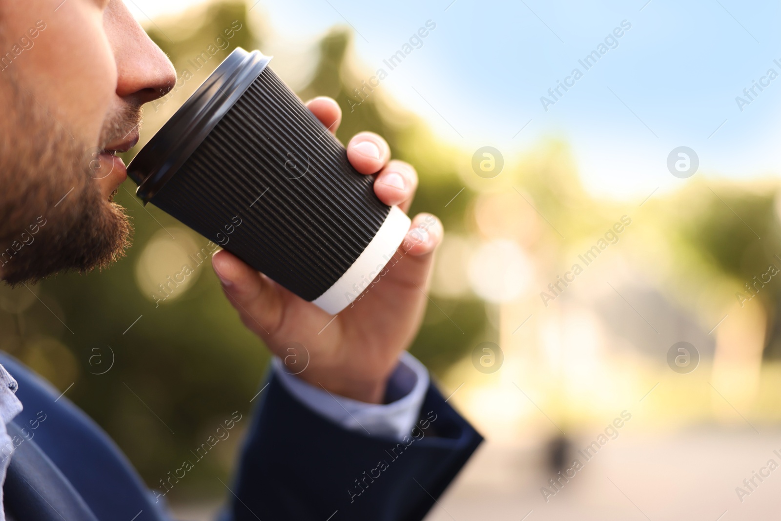 Photo of Coffee to go. Man with paper cup of drink outdoors, closeup. Space for text