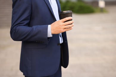 Photo of Coffee to go. Man with paper cup of drink outdoors, closeup. Space for text