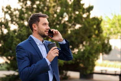 Photo of Coffee to go. Man with paper cup of drink talking on smartphone outdoors, space for text