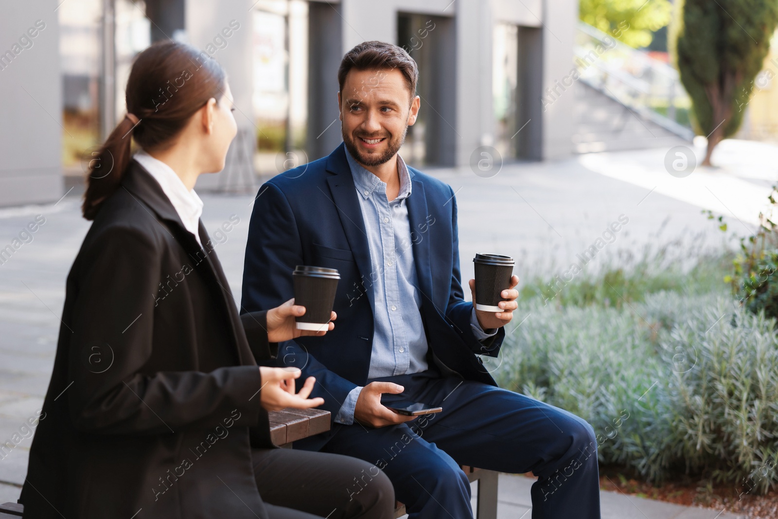 Photo of Coffee to go. Businesspeople with paper cups of drinks on bench outdoors, space for text