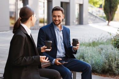 Photo of Coffee to go. Businesspeople with paper cups of drinks on bench outdoors, space for text