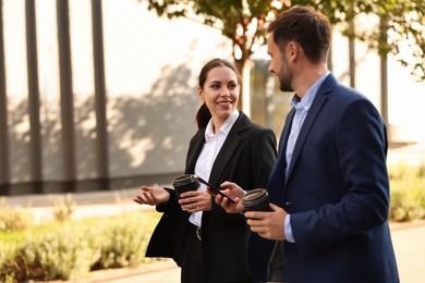 Photo of Coffee to go. Businesspeople with paper cups of drinks outdoors, space for text
