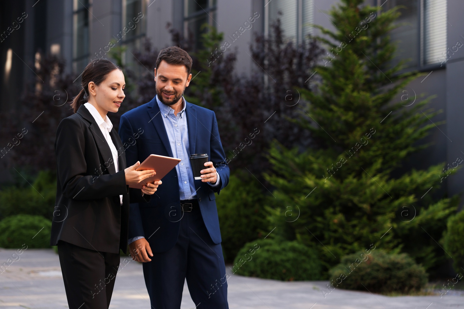 Photo of Coffee to go. Man with paper cup of drink and his business partner during meeting outdoors, space for text