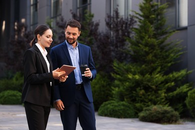 Photo of Coffee to go. Man with paper cup of drink and his business partner during meeting outdoors, space for text