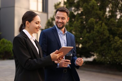 Photo of Coffee to go. Man with paper cup of drink and his business partner during meeting outdoors