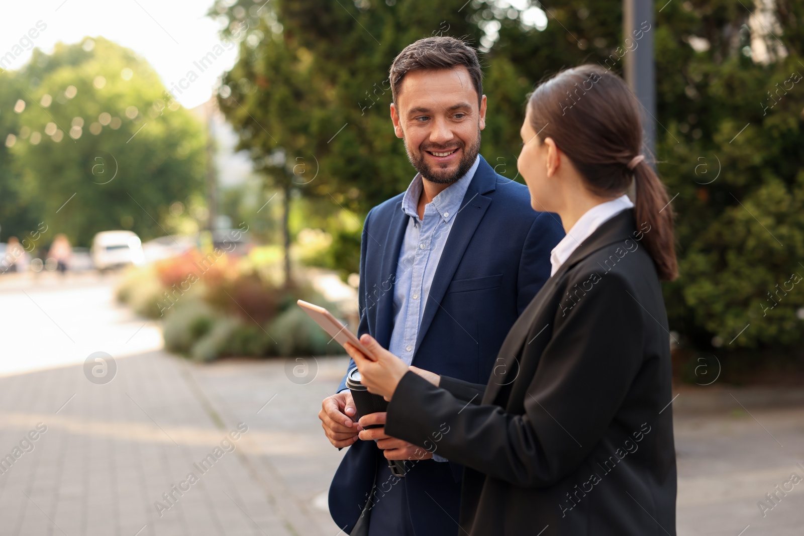 Photo of Coffee to go. Man with paper cup of drink and his business partner during meeting outdoors, space for text