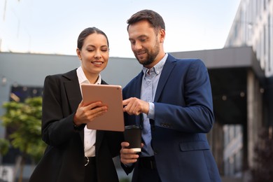 Photo of Coffee to go. Man with paper cup of drink and his business partner during meeting outdoors