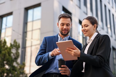Photo of Coffee to go. Man with paper cup of drink and his business partner during meeting outdoors, low angle view. Space for text