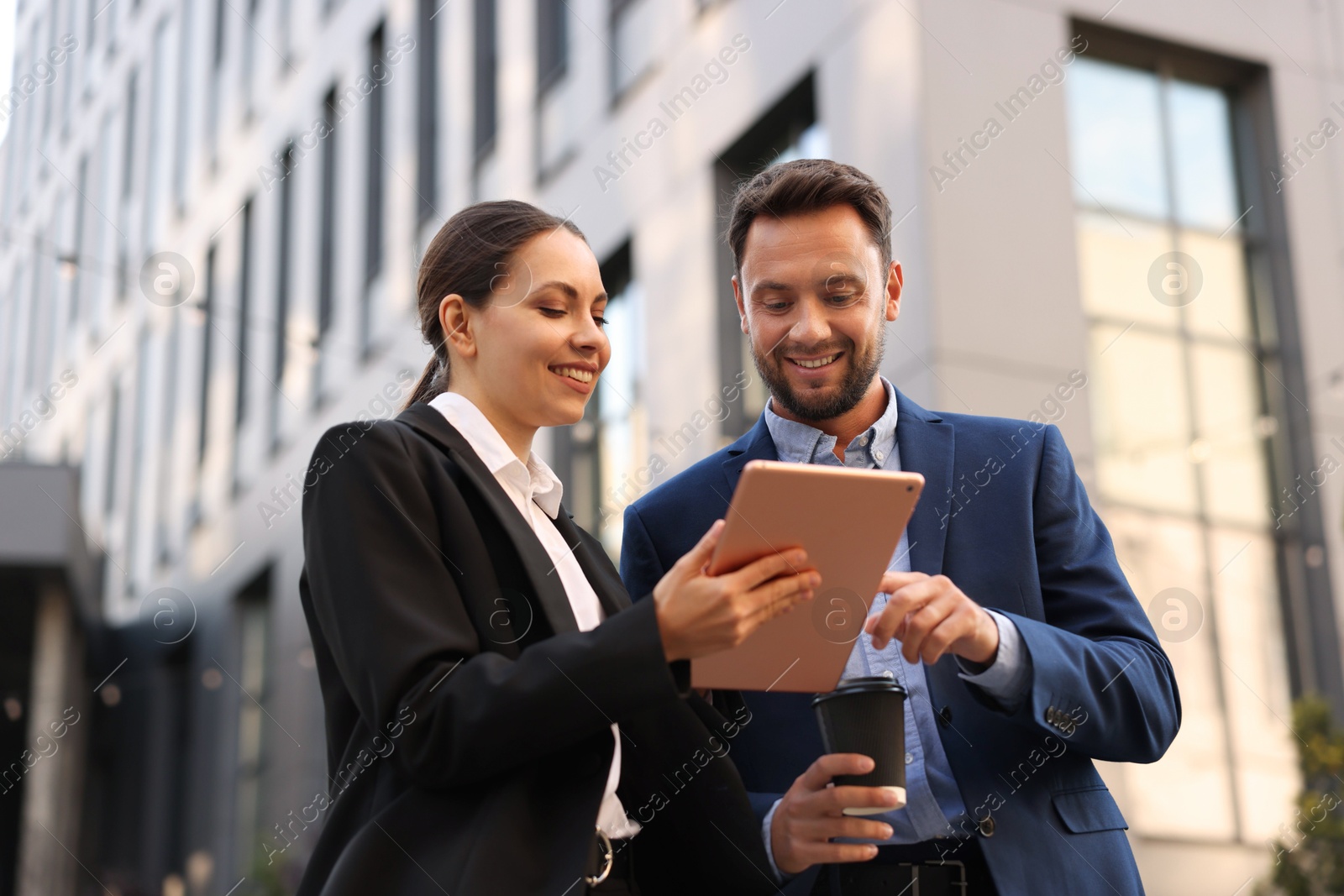 Photo of Coffee to go. Man with paper cup of drink and his business partner during meeting outdoors, low angle view