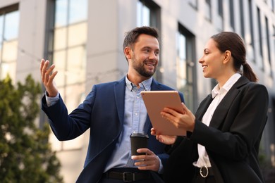 Photo of Coffee to go. Man with paper cup of drink and his business partner during meeting outdoors, low angle view