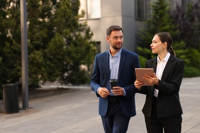 Photo of Coffee to go. Man with paper cup of drink and his business partner during meeting outdoors, space for text