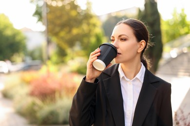 Photo of Coffee to go. Woman with paper cup of drink outdoors, space for text
