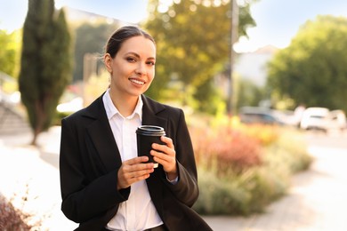 Photo of Coffee to go. Woman with paper cup of drink outdoors, space for text