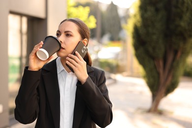 Photo of Coffee to go. Woman with paper cup of drink talking on smartphone outdoors, space for text