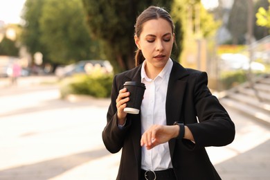 Photo of Coffee to go. Woman with paper cup of drink checking time outdoors, space for text