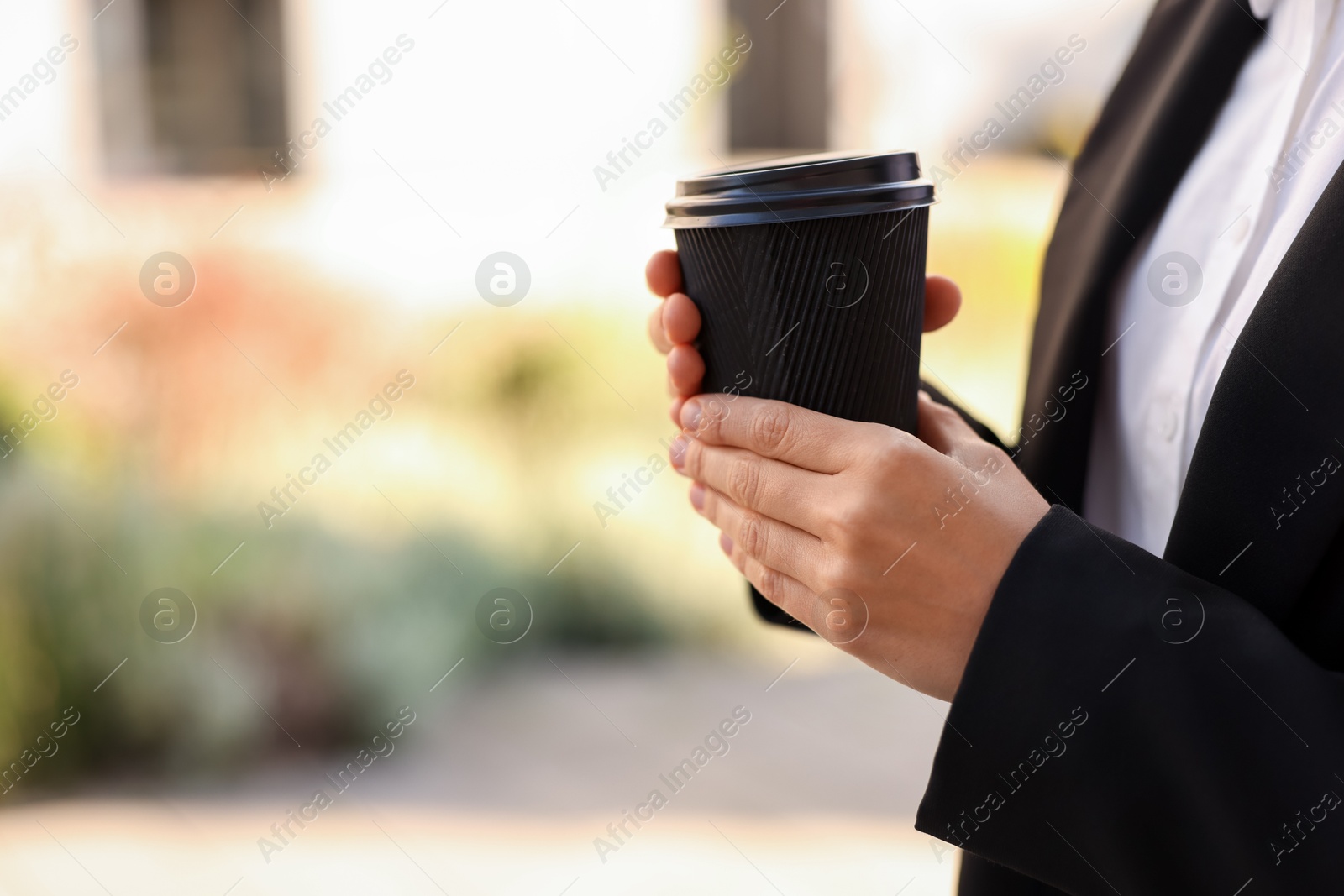 Photo of Coffee to go. Woman with paper cup of drink outdoors, closeup. Space for text