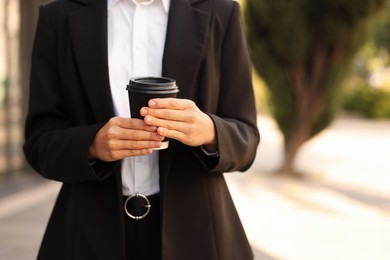Photo of Coffee to go. Woman with paper cup of drink outdoors, closeup. Space for text
