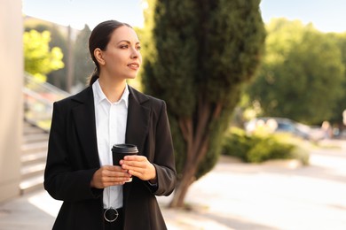 Photo of Coffee to go. Woman with paper cup of drink outdoors, space for text