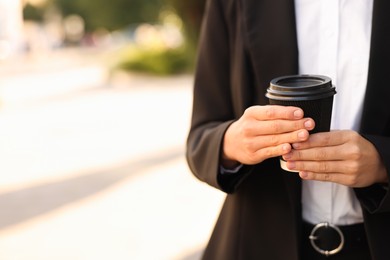 Photo of Coffee to go. Woman with paper cup of drink outdoors, closeup. Space for text