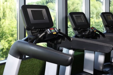 Photo of Many modern treadmills near window in gym