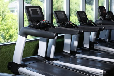 Photo of Many modern treadmills near window in gym