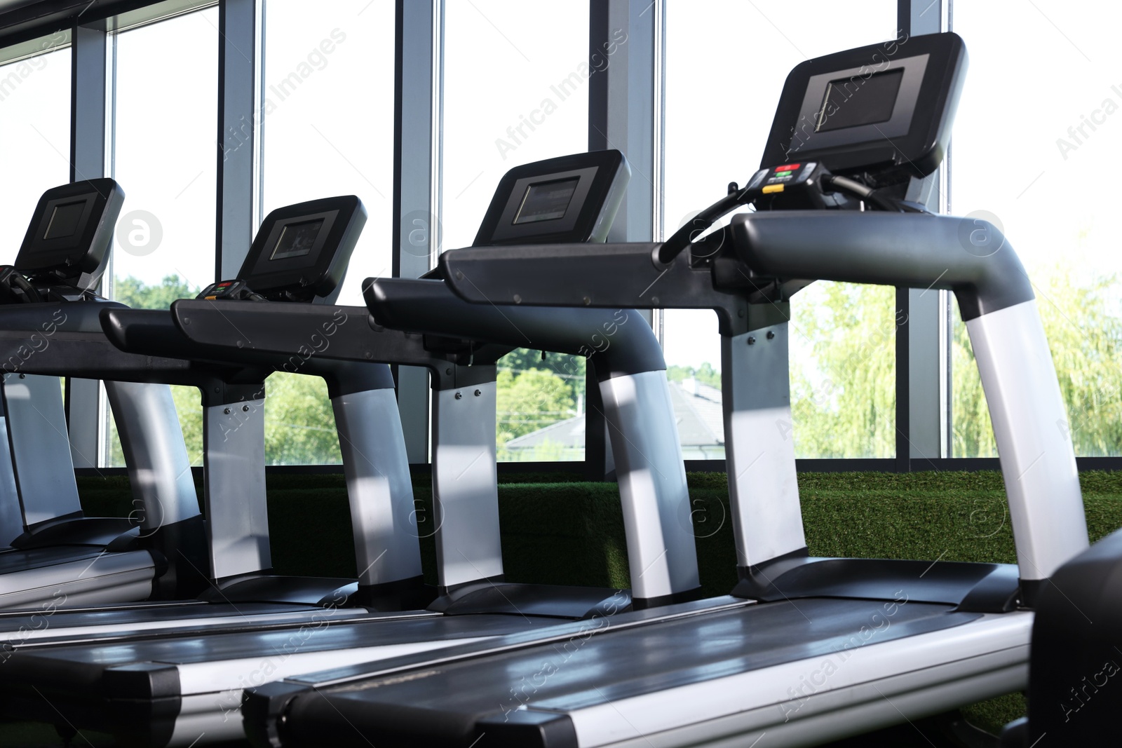 Many modern treadmills near window in gym, low angle view Photo of Many modern treadmills near window in gym, low angle view