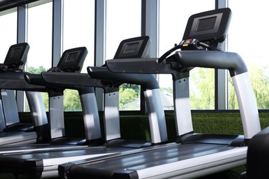 Photo of Many modern treadmills near window in gym, low angle view