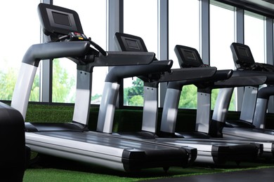 Photo of Many modern treadmills near window in gym, low angle view